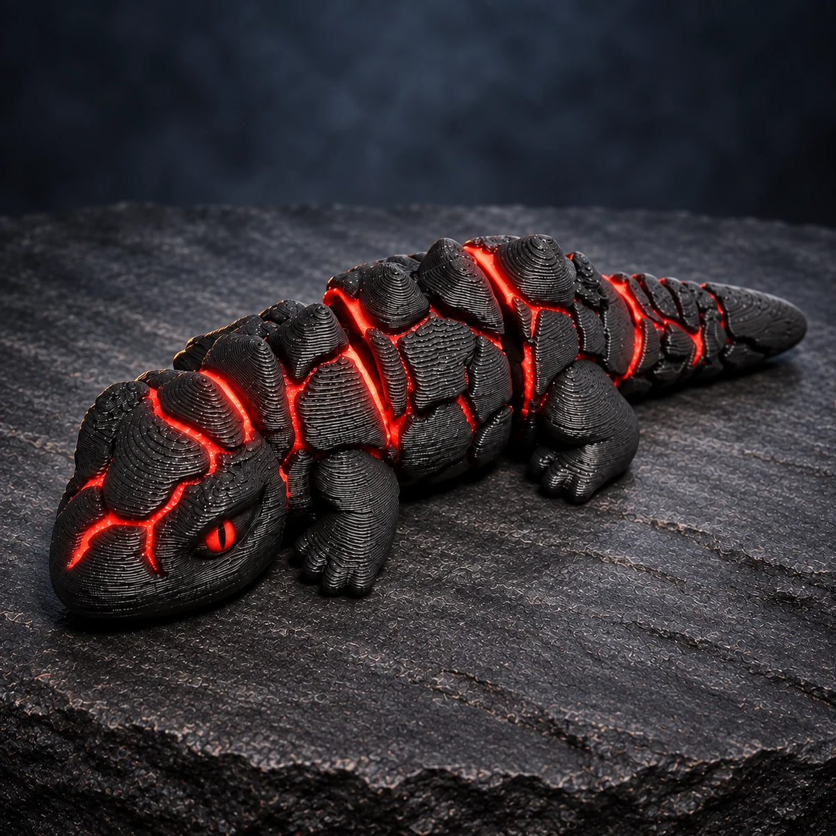 Lava Lizard articulated fidget with black rock-like plates, glowing red details and a red iris with black slit pupil, on volcanic slate.
