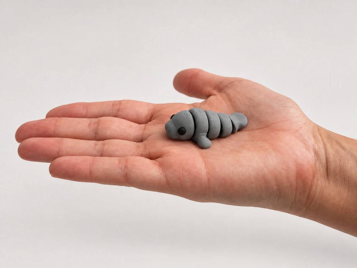 Mabel (Manatee) articulated fidget resting in an open hand.