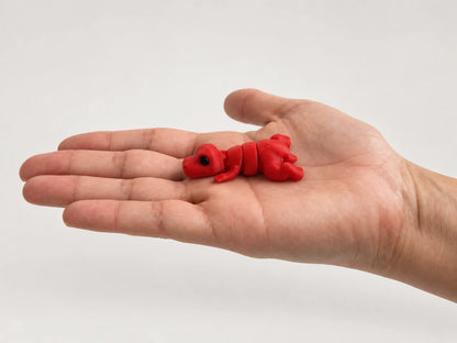 Timmy (T-Rex) articulated fidget resting in an open hand.